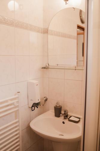 a white bathroom with a sink and a mirror at Penzion Harmonia in Liptovský Mikuláš