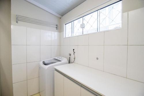 Un baño con lavadora y secadora y una ventana. en JOA23 - 1 Dorm, Climatizado, Garagem, TV Smart, en Balneário Camboriú