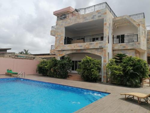a villa with a swimming pool in front of a building at Belle location familiale in Abomey-Calavi