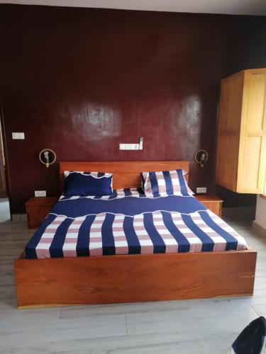 a large wooden bed with blue and white striped sheets at Belle location familiale in Abomey-Calavi