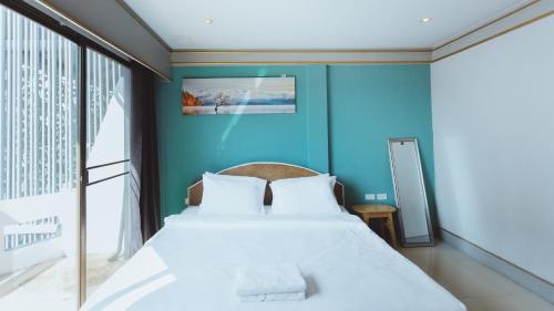 a bedroom with a large bed with a blue wall at X Mitr Inn Nimman มิตร อินน์ นิมมาน 12 in Chiang Mai