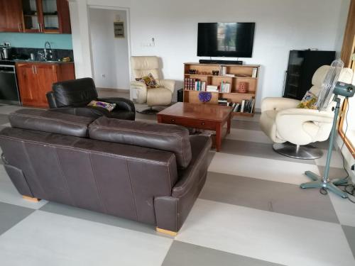 a living room with a brown leather couch and chairs at Belle location familiale in Abomey-Calavi