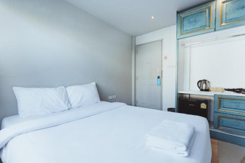 a bedroom with a white bed and a kitchen at X Mitr Inn Nimman มิตร อินน์ นิมมาน 12 in Chiang Mai