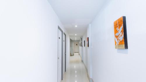 a hallway with white walls and a painting on the wall at X Mitr Inn Nimman มิตร อินน์ นิมมาน 12 in Chiang Mai