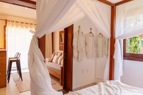 a bedroom with a bed with white curtains at Villa Estrela Bungalow in Itacaré