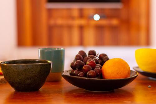 a bowl of fruit and an orange on a table at Villa Estrela Bungalow in Itacaré