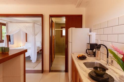 a kitchen with a sink and a refrigerator and a bedroom at Villa Estrela Bungalow in Itacaré