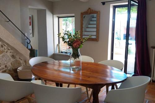a wooden table with white chairs and a vase with flowers at Le Mas Lolivo in Aubignan