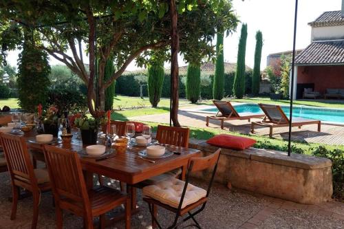 a wooden table and chairs in a yard with a pool at Le Mas Lolivo in Aubignan