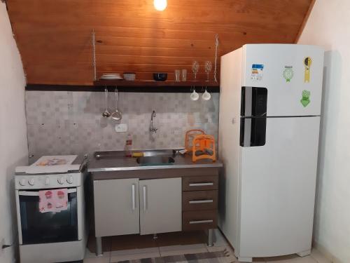 a small kitchen with a white refrigerator and a sink at Chalé Floresta in Paraty