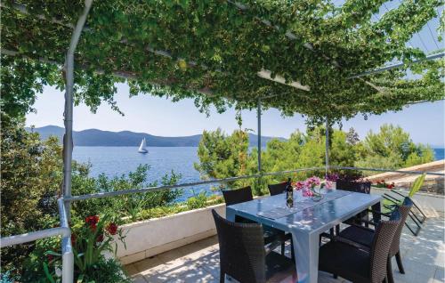 a table and chairs on a patio with a view of the water at Two-Bedroom Apartment In Ratac in Orasac