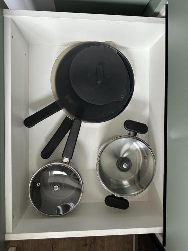 two pots and pans in a white drawer at AC apartaments Daugavpils Central in Daugavpils