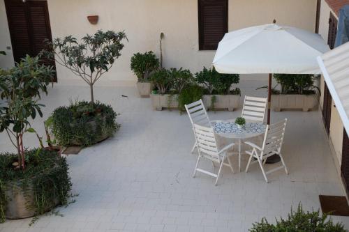 a patio with a table with an umbrella and chairs at Casa Kaukana - A Pochi Passi dal Mare in Villaggio Azzurro
