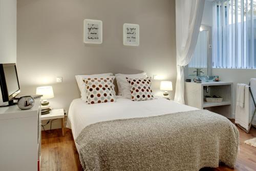 une chambre blanche avec un lit et une télévision dans l'établissement Beauregard central residence, à Paris