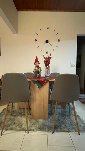 a dining room table with a clock on the wall at My Sweet Home in Tríkala