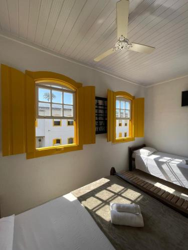 a bedroom with a bed with a ceiling fan and windows at Pousada Fortaleza in Paraty