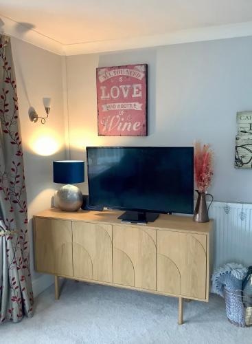 a flat screen tv sitting on top of a wooden cabinet at Lorton Villa with a Log Burner in Saint Helens