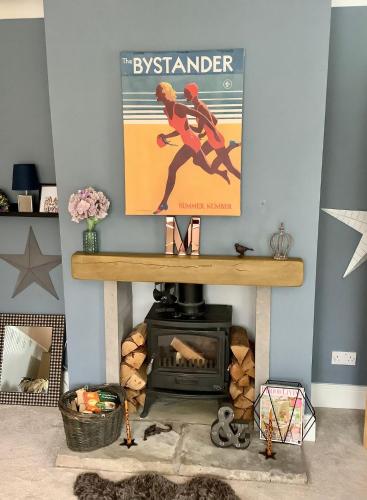 a living room with a fireplace and a poster at Lorton Villa with a Log Burner in Saint Helens