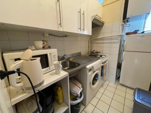 une cuisine avec un évier et une machine à laver dans l'établissement appartement pres de la tour eiffel, à Paris