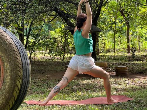 a woman doing a yoga pose next to a tire at Ali Adi Eco Tree House in Sigiriya