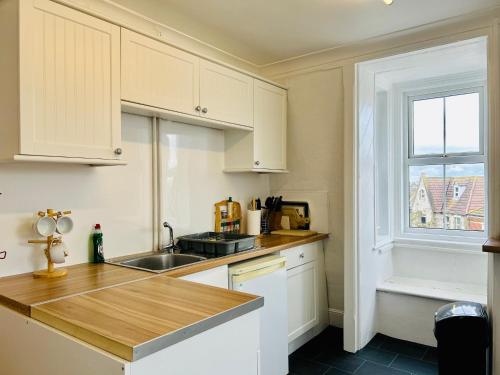 a kitchen with white cabinets and a sink and a window at Clarence Quarters Vintage Seafront Guest House in Portsmouth