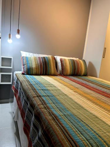 a bedroom with a large bed with a colorful blanket at Cosy Studio Apartament - Arujá SP in Arujá