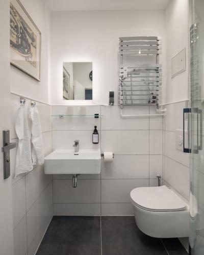 a white bathroom with a toilet and a sink at Boardinghouse Hohenzollern in Berlin