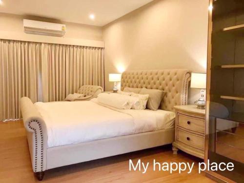a bedroom with a large white bed and a dresser at My Happy Place in Nonthaburi