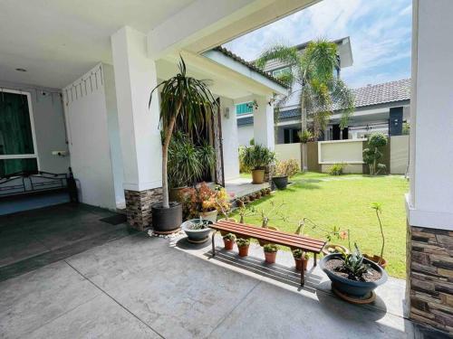 a porch of a house with potted plants and a bench at Bungalow in exclusive area in Nibung Tebal