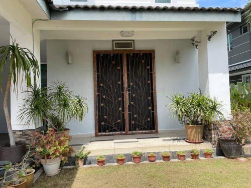 a front door of a house with potted plants at Bungalow in exclusive area in Nibung Tebal