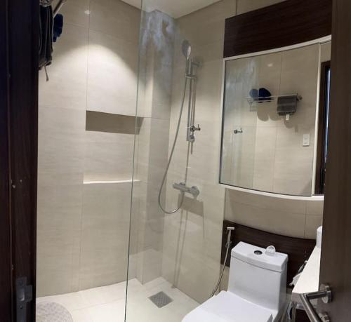 a bathroom with a toilet and a glass shower at Tambuli Seaside Residences Tower C Seaview balcony pool 18mins Aiport in Lapu Lapu City