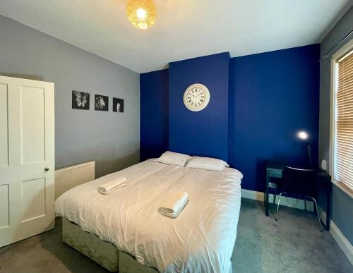 a blue bedroom with a bed with a clock on the wall at Stylish 3-Bedroom Home! in Bedworth