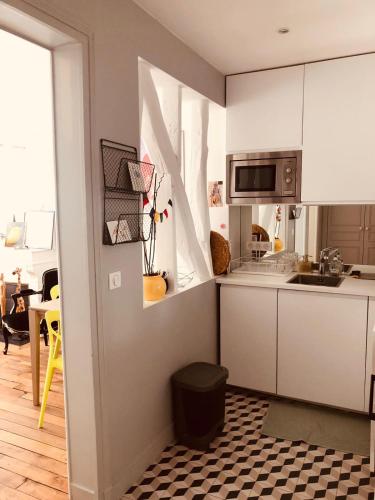 - une cuisine avec des placards blancs et un sol noir et blanc dans l'établissement appartement Cozy Paris Canal St Martin, à Paris
