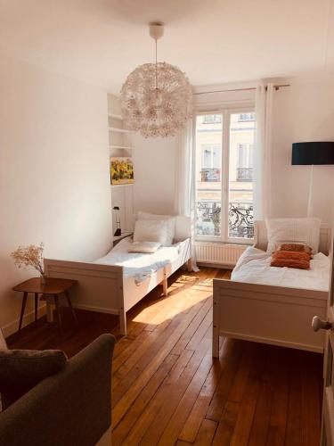 - un salon avec deux lits et un lustre dans l'établissement appartement Cozy Paris Canal St Martin, à Paris