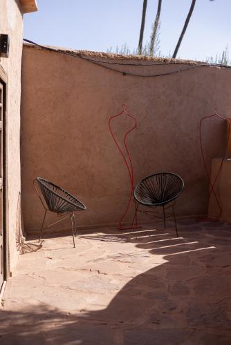 two chairs sitting next to a wall with a painting on it at Jnane Allia in Douar Soukkane