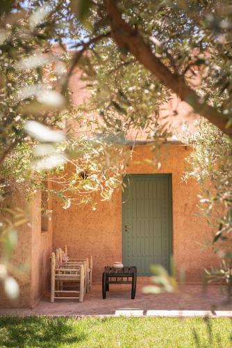 a patio with chairs and a table and a green door at Jnane Allia in Douar Soukkane