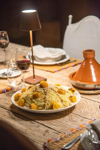 a plate of food on a table with a glass of wine at Jnane Allia in Douar Soukkane