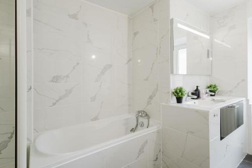 une salle de bain blanche avec une baignoire et un lavabo dans l'établissement Appart design au cœur de Belfort, à Belfort