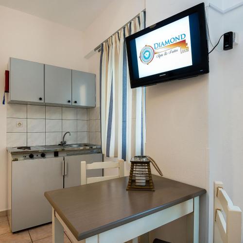 a kitchen with a table and a tv on the wall at Diamond Apartments & Suites in Hersonissos