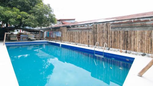 a swimming pool with blue water next to a wooden fence at RedDoorz at DBuilders Rooms Lower Bicutan in Manila
