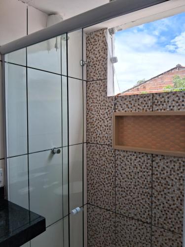 a glass shower door in a bathroom with a brick wall at Aconchego paraty in Paraty