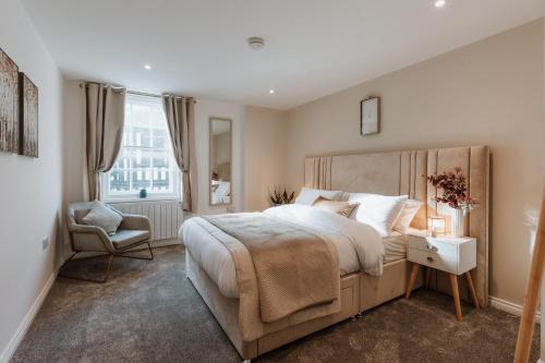 a bedroom with a large bed and a chair at 2 Bed Apartment Overlooking the Square Step Out to Shops & Dining in Shrewsbury