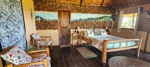 a bedroom with a bed and a chair in a room at Agandi Uganda Eco-lodges in Bwindi