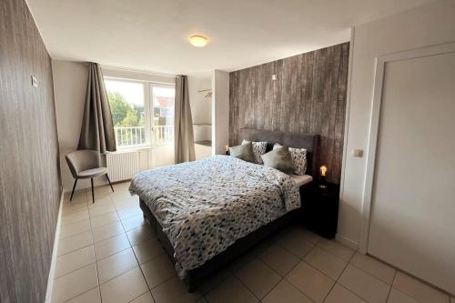 a bedroom with a bed and a chair and a window at Bright, spacious apartment nearby beach in Ostend