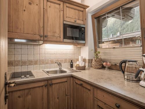 a kitchen with wooden cabinets and a sink at Apparthotel "Landhaus Veronika" in Mayrhofen
