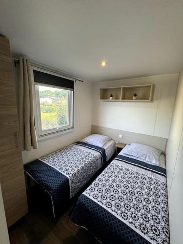 deux lits dans une petite pièce avec une fenêtre dans l'établissement Mobile Home 168 pour 6 pers Camping Siblu Lac des Rêves Perols, à Lattes