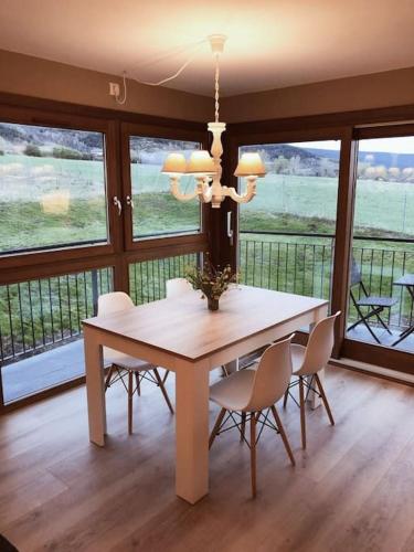 une salle à manger avec une table, des chaises et des fenêtres dans l'établissement Apartamento en Sainte Leocadie, à Sainte-Léocadie