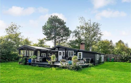 a black house in a yard with green grass at Nice Home In Tisvildeleje With Kitchen in Tisvildeleje