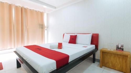 a bedroom with a bed with a red and white blanket at RedDoorz at DBuilders Rooms Lower Bicutan in Manila