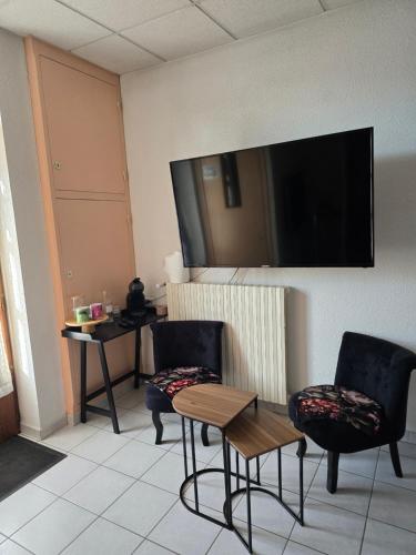 a room with two chairs and a table and a flat screen tv at Chambre indépendante in Les Avenières